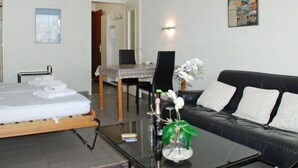 Et moderne hotelværelse med en seng, et glasbord, en sort lædersofa og et billede på væggen.