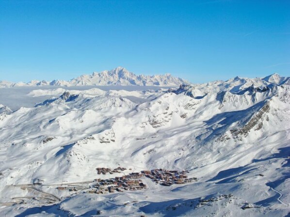 Paisaje montañoso cubierto de nieve con un pequeño asentamiento en primer plano.