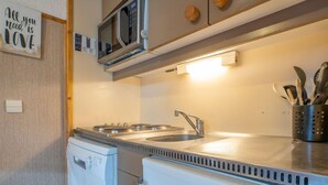 A compact kitchen with a microwave, a sink, and a refrigerator. - Arcelle 203 by Interhome (Val Thorens)