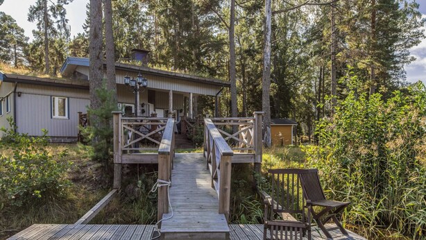 A wooden deck leading to a cabin with a porch and a chair. - Vacation home Björn by Interhome (Kemiönsaari)