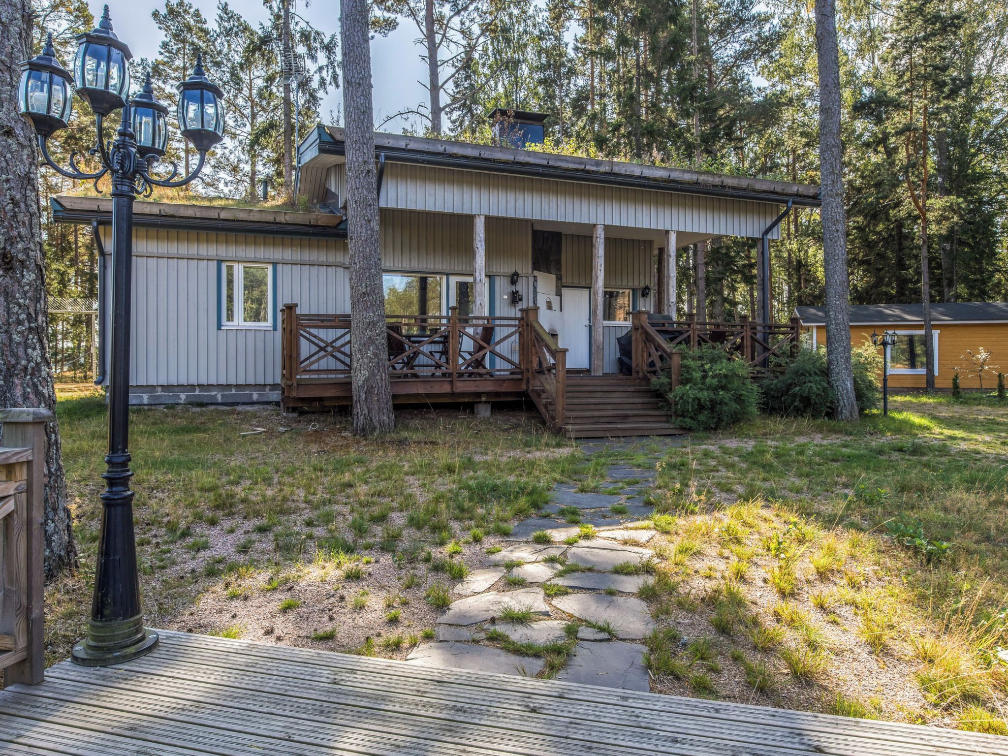 A cabin with a porch, a stone pathway, and a forested backdrop.