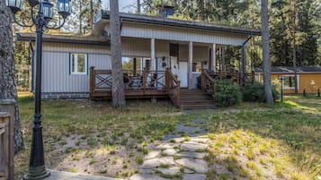 A cabin with a porch, a stone pathway, and a forested backdrop.