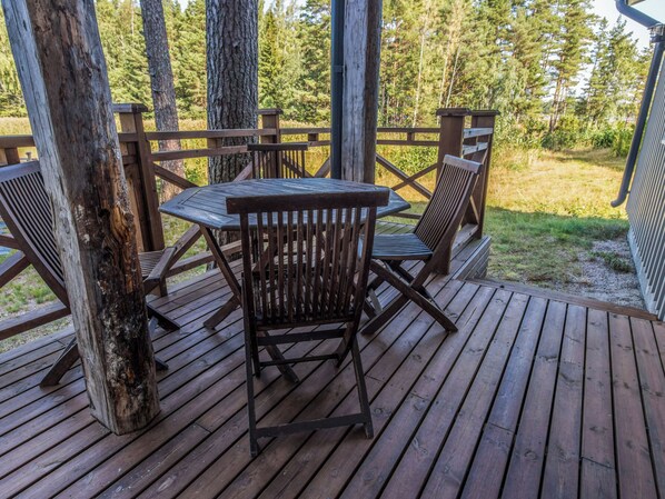 A wooden deck with a table and chairs, surrounded by trees.