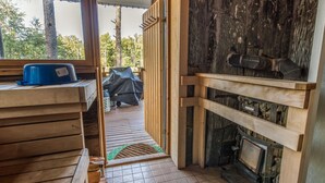 A wooden cabin interior with a fireplace, a covered outdoor seating area, and a view of the surrounding forest. - Vacation home Björn by Interhome (Kemiönsaari)