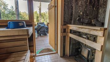 Interior de madera con chimenea, un banco y una puerta que da al exterior.