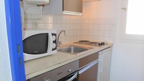 A compact kitchen with a microwave, sink, stove, and dishwasher. - Les Occitanes by Interhome (Gruissan)