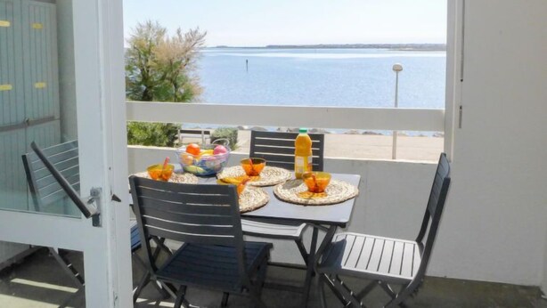 A balcony with a table set for two, overlooking a body of water. - Les Occitanes by Interhome (Gruissan)
