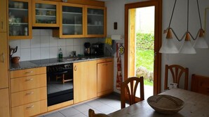 Una cocina con muebles de madera, una estufa y un comedor con una mesa y sillas.
