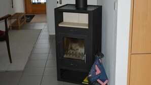 Una sala de estar moderna con un estufa de leña negra, un banco de madera y suelo de baldosas.