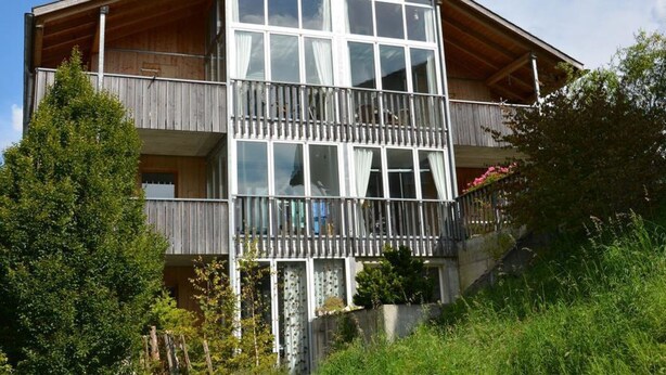 Un edificio de madera de dos pisos, con ventanas amplias y balcones.