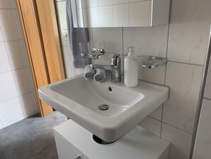 Une salle de bain avec un lavabo blanc, un miroir et un porte-serviettes.