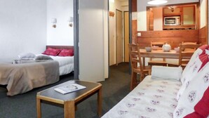 Une chambre d’hôtel compacte comprenant un lit, une petite table, un canapé, une table à manger avec des chaises et une kitchenette équipée d’un four à micro-ondes.