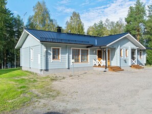 A two-story light blue cabin with a dark blue roof, wooden windows, and a porch with steps leading to the entrance. - Vacation home Repo by Interhome (Sotkamo)
