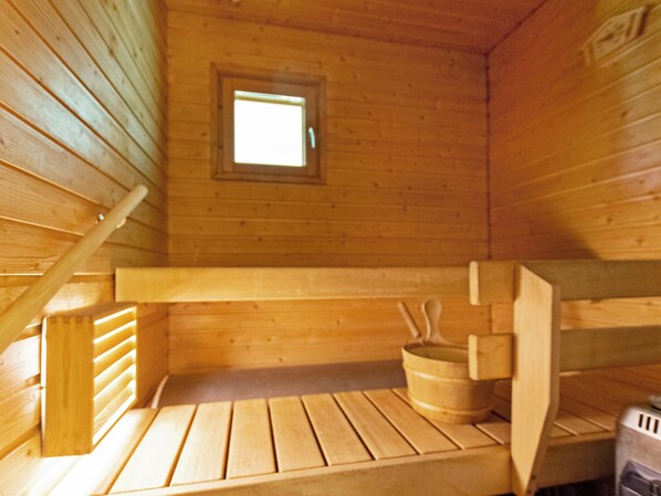 A wooden cabin interior with a small window, wooden benches, and a wooden bucket. - Vacation home Repo by Interhome (Sotkamo)