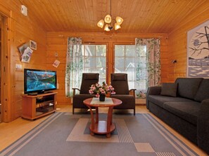 A cozy cabin interior with a television, two chairs, a sofa, and a small table with flowers. - Vacation home Repo by Interhome (Sotkamo)