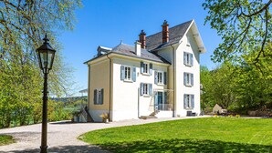 A large, two-story house with a well-maintained lawn and a gravel driveway. - Monchateau étoilé Hébergement insolite (Merlas)