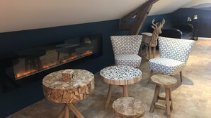 A modern lounge area with a fireplace, patterned chairs, and a unique wooden coffee table. - Monchateau étoilé Hébergement insolite (Merlas)