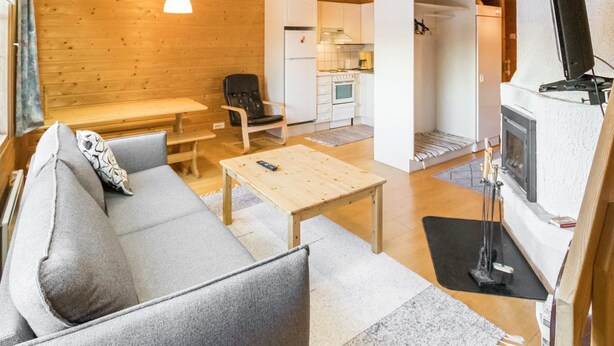 Interior acogedor de una cabaña con sofá, mesa y chimenea.
