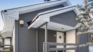 Una casa con porche cubierto, una puerta marcada 'K1' y un pequeño espacio de terraza.
