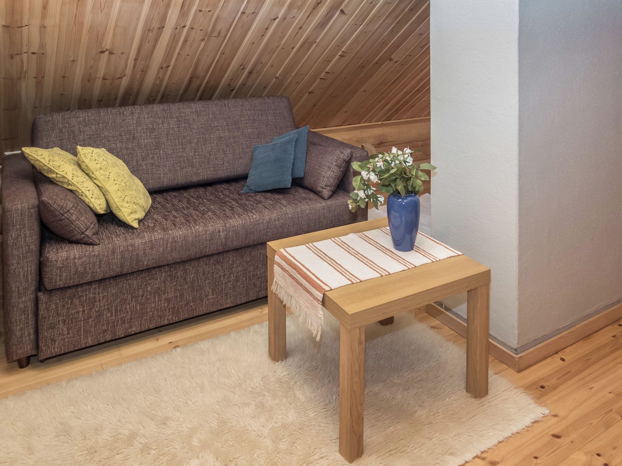 Une pièce chaleureuse avec un canapé marron, une petite table en bois et une plante en pot.