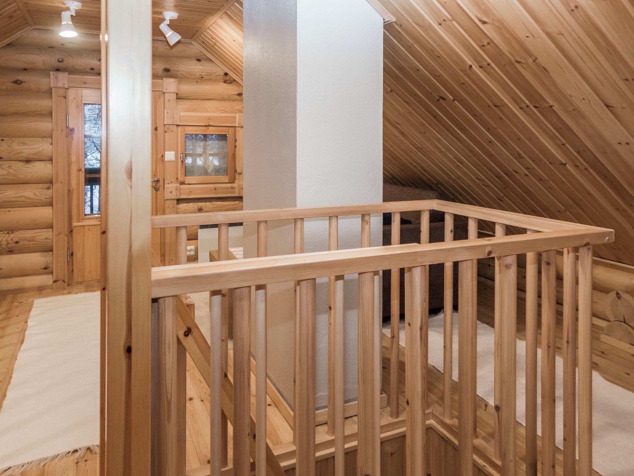A wooden interior with a visible staircase and a white pillar.