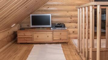 A wooden cabin interior with a television, DVD player, and a small cabinet.