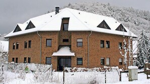 Un edificio grande de varios pisos, de ladrillo, con techo nevado y una entrada central.