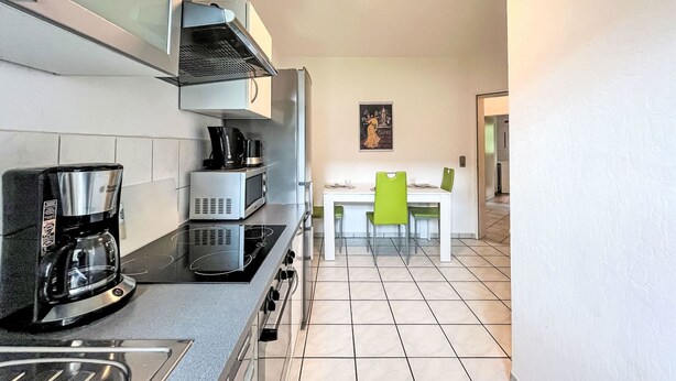 Una cocina moderna equipada con cafetera, microondas y estufa. Hay una zona de comedor con mesa y sillas.