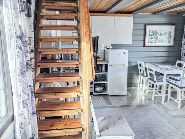 A kitchen with white cabinets, a white refrigerator, and a dining area with white chairs and a table.