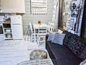 A compact living space with a kitchenette, a dining area, and a sofa with patterned cushions.