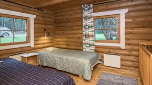 Acogedora habitación tipo cabaña de madera con dos camas, una ventana con vista a árboles, una lámpara en el techo y un calentador.