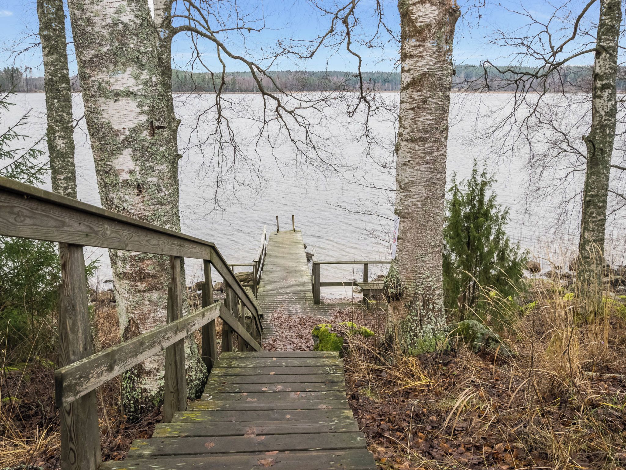 A wooden staircase leading to a dock over a frozen lake, surrounded by trees.