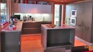 Una cucina moderna con isola centrale, elettrodomestici integrati e ampie finestre.