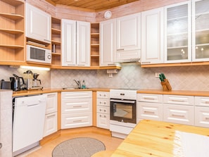 Una cocina compacta con armarios blancos, horno integrado, microondas y lavavajillas.