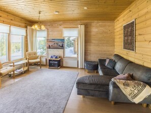 A cozy living room with a sofa, armchair, and a television.