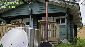 Un jacuzzi installé à l’extérieur d’une maison, avec une terrasse en bois et une structure métallique.