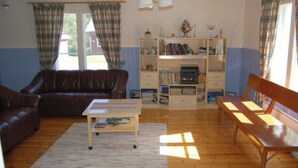Un salon avec un canapé en cuir marron, un banc en bois, une petite table et une bibliothèque.