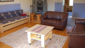 Un salon chaleureux avec un canapé, un fauteuil en cuir marron, une petite table en bois et une cheminée.