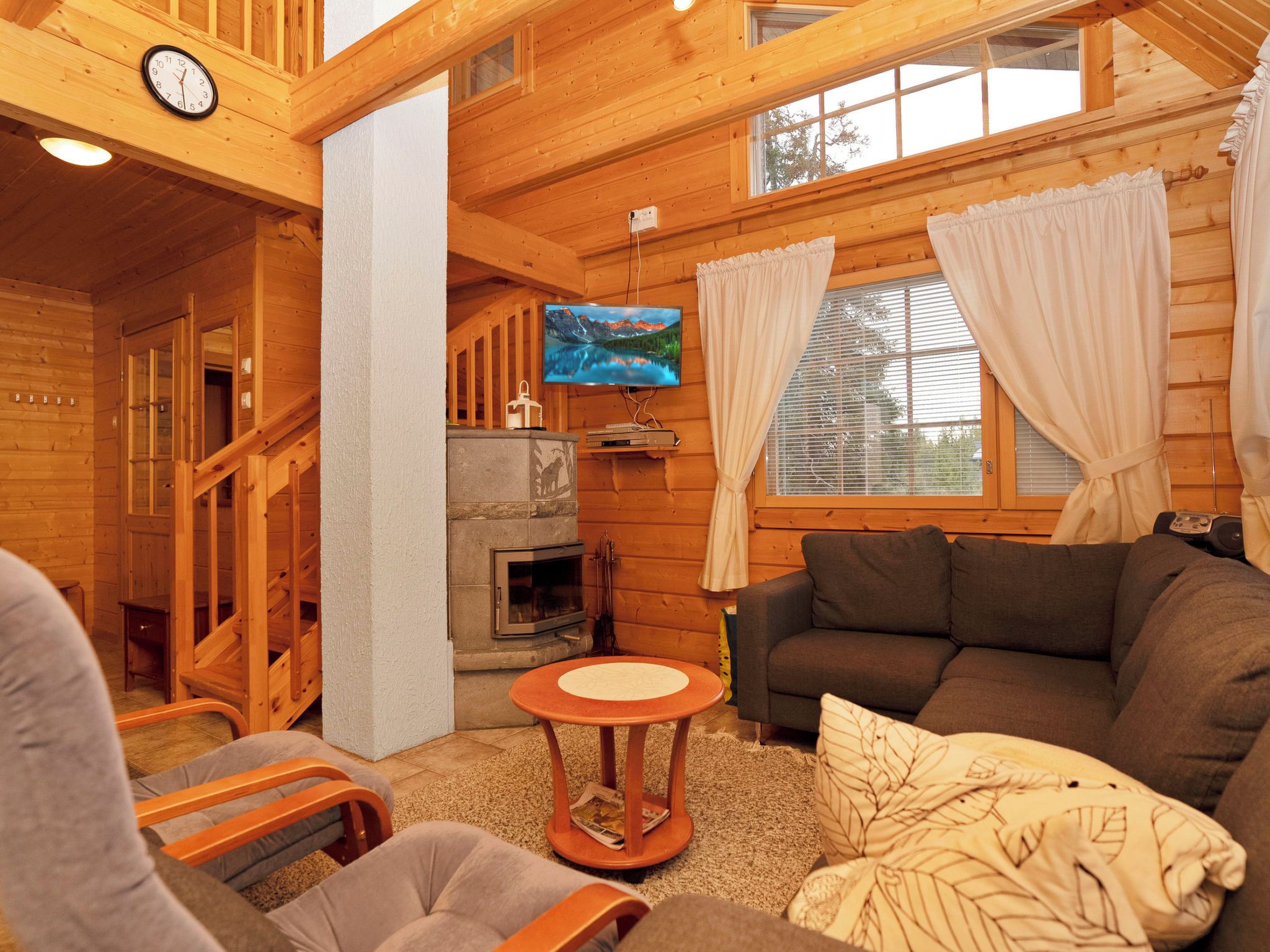 L’intérieur d’un chalet confortable, avec des murs en bois, une cheminée, un téléviseur et un coin salon accueillant.