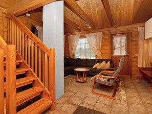 A wooden interior with a staircase, a sofa, a small round table, and a chair.