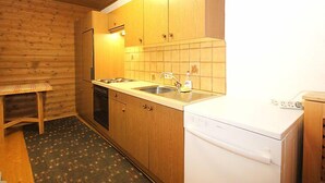 Una cocina compacta con armarios de madera, lavavajillas y salpicadero de azulejos.