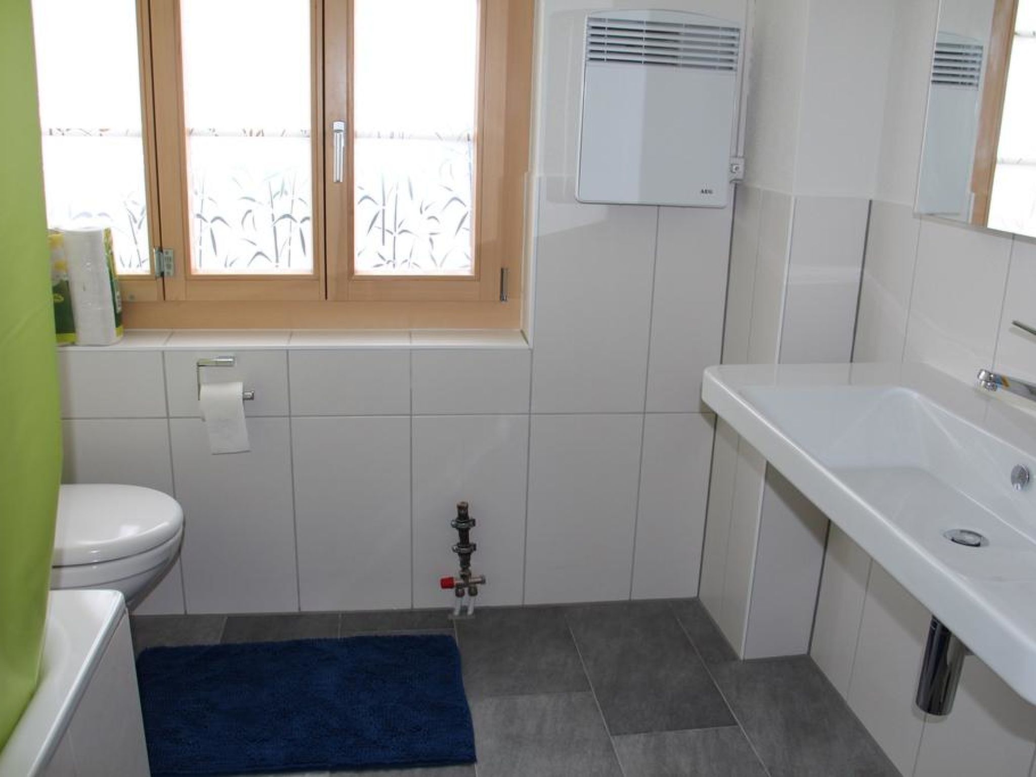 Et badeværelse med toilet, håndvask og vindue.