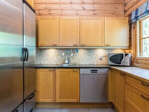 A kitchen with wooden cabinets, a stainless steel refrigerator, a Siemens dishwasher, and a microwave. - Villa kotikoivu by Interhome (Ristiina)