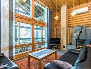 L’intérieur d’une cabane en rondins, avec une cheminée, un téléviseur et un coin salon.