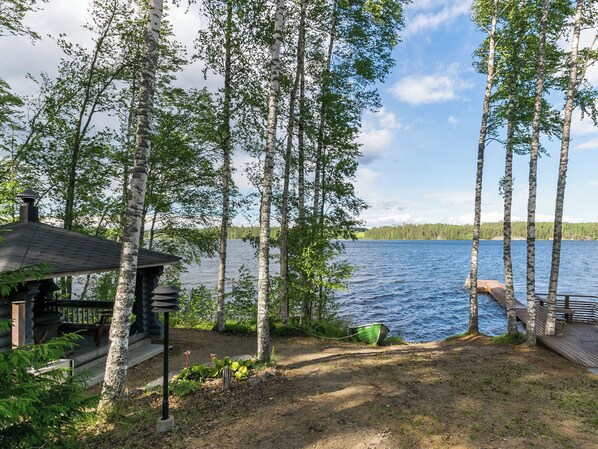 A lakeside cabin with a dock, surrounded by birch trees and a clear view of the lake.