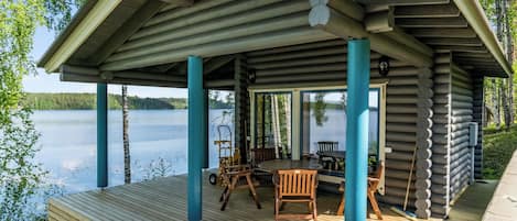 Une terrasse en bois avec un espace salon couvert donnant sur un lac.