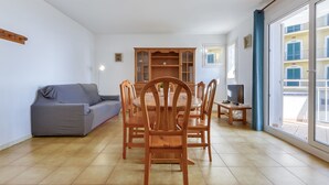 A dining area with a wooden table and chairs, a grey sofa, and a wooden cabinet. - Platja de Roses by Interhome (Roses)