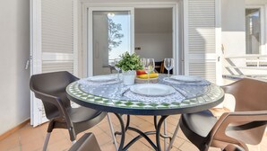 An outdoor dining area with a round table, chairs, and a view of the interior through an open door. - Platja de Roses by Interhome (Roses)