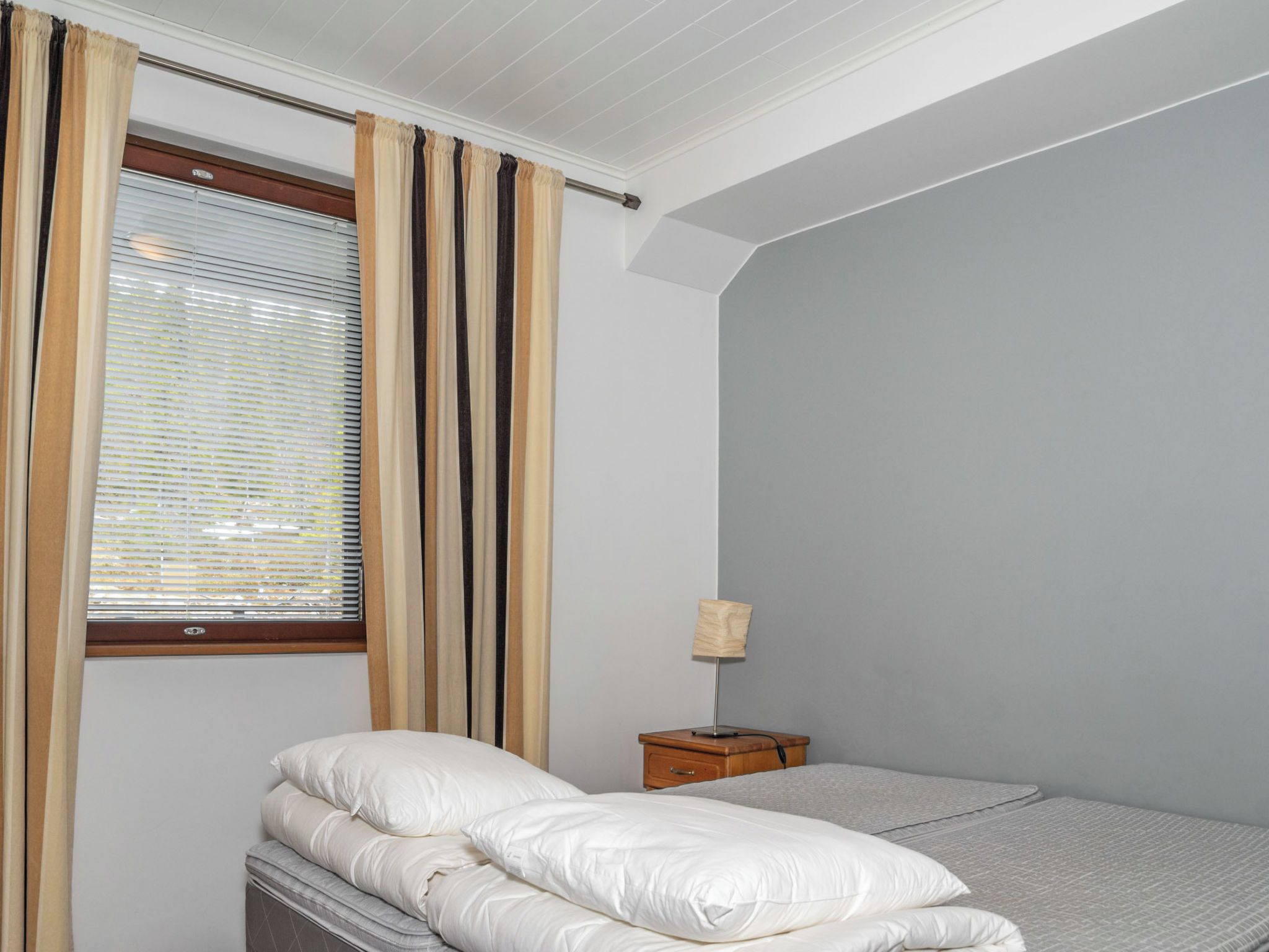 Una camera da letto con un letto, un comodino, una lampada e una finestra con tende.