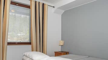 Una camera da letto con un letto, un comodino, una lampada e una finestra con tende.